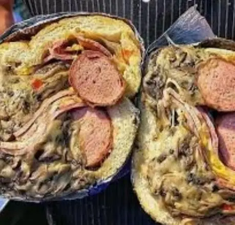 دو نیمه از یک ساندویچ پرملات و بزرگ فست فود گلها با لایه‌های ضخیم سوسیس، ژامبون و مخلفات خوشمزه برای یک وعده کامل.