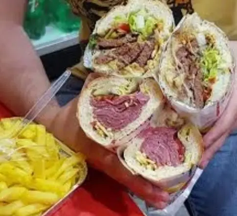 چند ساندویچ بزرگ پرحجم شامل گوشت، ژامبون و مخلفات به همراه سیب زمینی سرخ کرده در فست فود پیتزا و ساندویچ گلها. خوشمزه و تازه.