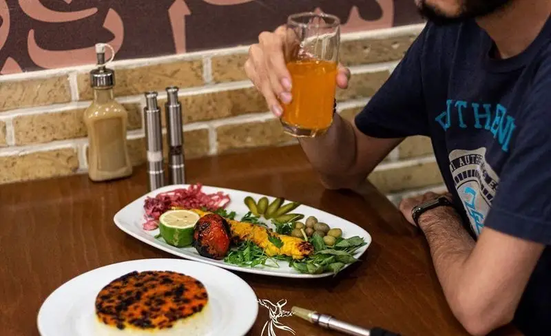 تصویری جذاب از کباب جوجه آبدار، ته دیگ زعفرانی و نوشیدنی گوارا در کافه رستوران درویش. لذت یک وعده غذایی فراموش‌نشدنی را تجربه کنید.