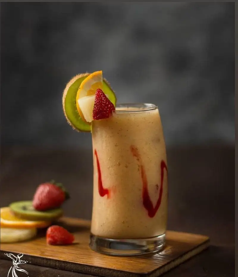 اسموتی میوه‌ای تازه و لذیذ کافه رستوران درویش، با تزئینات زیبای کیوی، توت فرنگی، پرتقال و سس قرمز؛ نوشیدنی خنک و انرژی‌بخش.