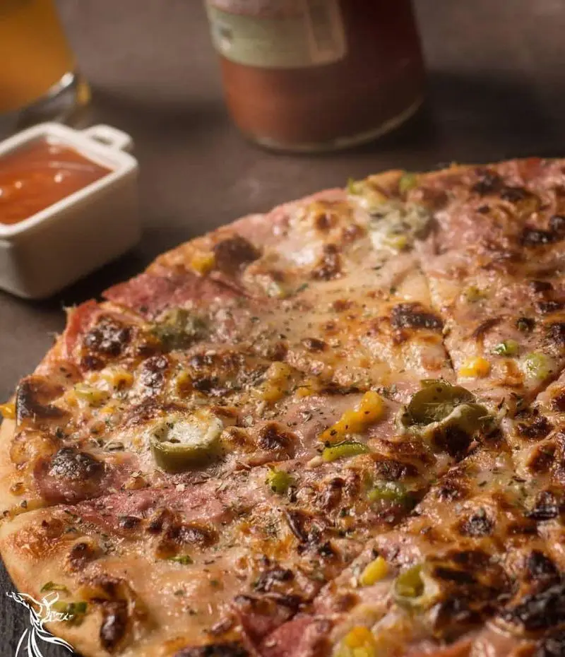 پیتزای داغ و تازه از کافه رستوران درویش، با پنیر آب شده، ژامبون، فلفل هالوپینو و ذرت. طعمی فراموش‌نشدنی برای ناهار و شام شما.