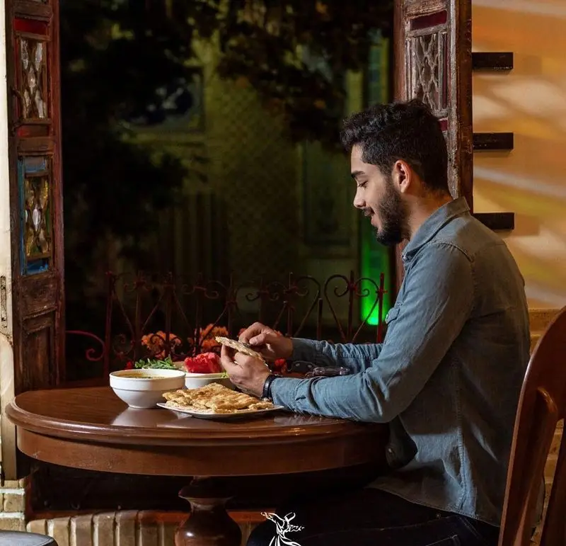 کافه رستوران درویش: مردی جوان در فضایی سنتی و دلنشین، از صرف غذای اصیل ایرانی شامل نان تازه لذت می برد. انتخابی عالی.