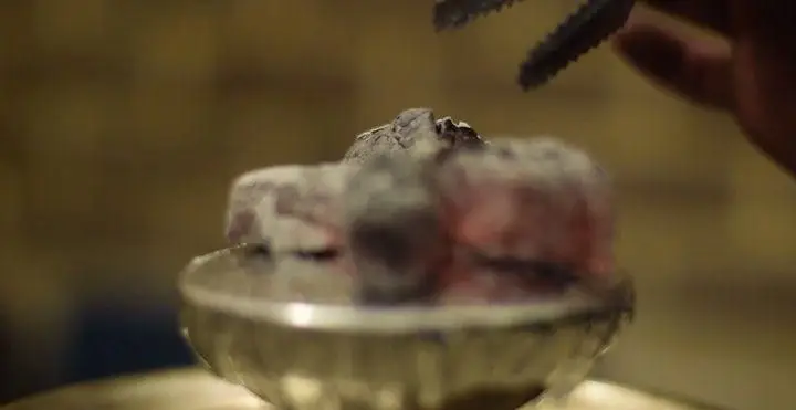 آماده‌سازی قلیان با ذغال‌های گداخته در کافه رستوران درویش برای تجربه‌ای دلنشین و آرامش‌بخش از نوشیدنی و قلیان.