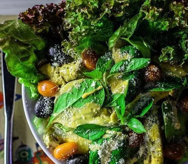 سالاد رنگارنگ و سالم بیگ بنگ شامل کاهو تازه، زیتون سیاه، گوجه گیلاسی نارنجی و ریحان معطر با سس مخصوص و پنیر رنده شده.