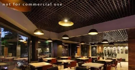 محیط داخلی رستوران بیگ بنگ، طراحی مدرن با پنجره‌های بزرگ، سقف شبکه‌ای، نورپردازی گرم و میز و صندلی‌های راحت برای تجربه‌ای دلپذیر.