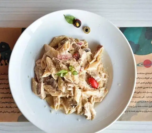 بشقاب پاستا پنه چیکن و قارچ با سس آلفردو خامه ای و تزئین زیتون و گوجه فرنگی، غذایی محبوب در بیگ بنگ.