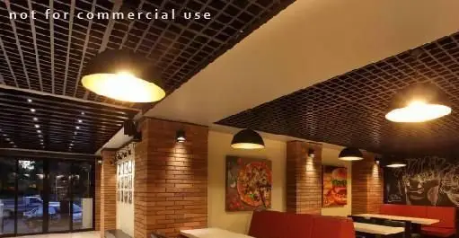 فضای داخلی مدرن و جذاب رستوران بیگ بنگ با سقف مشبک، دیوارهای آجری، چراغ‌های آویز و مبلمان قرمز برای محیطی دلپذیر.