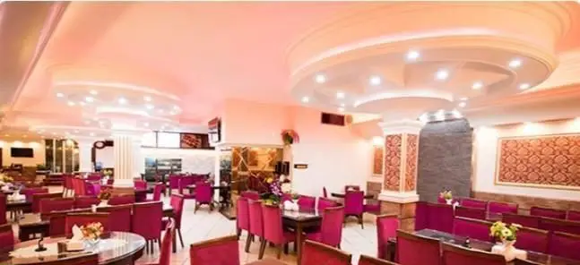 فضای داخلی لوکس و دلنشین رستوران ایرانی کلانتر با دکوراسیون شیک، میز و صندلی‌های قرمز و نورپردازی زیبا برای تجربه غذای ایرانی اصیل