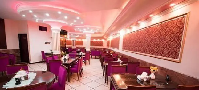 محیط داخلی زیبا و دلنشین رستوران ایرانی کلانتر، با دکوراسیون شیک و صندلی‌های بنفش، ایده‌آل برای لذت بردن از غذاهای سنتی ایرانی.