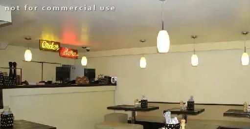 دکوراسیون داخلی رستوران پیتزا اسپایسی، یک رستوران ایتالیایی مدرن با میزهای مرتب، پیشخوان سفارش و نورپردازی گرم.