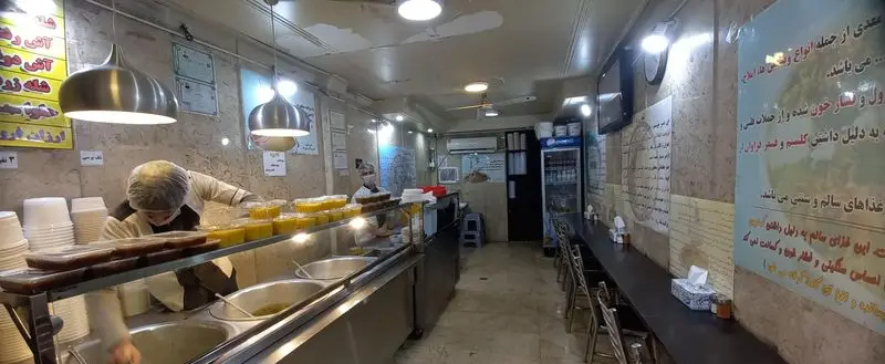 نمای داخلی آش علی بابا، آش فروشی سنتی با کارکنان فعال، پیشخوان پر از آش‌های خوشمزه و محیطی صمیمی برای سرویس‌دهی سریع.