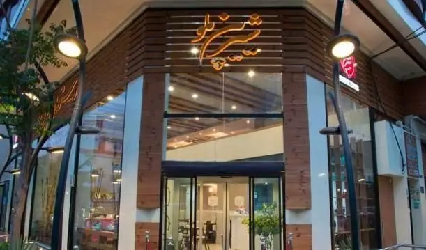 نمای بیرونی رستوران فرنگی شیرین پلو با طراحی مدرن، ورودی شیشه‌ای و تابلوی درخشان نام رستوران، محیطی جذاب برای مشتریان