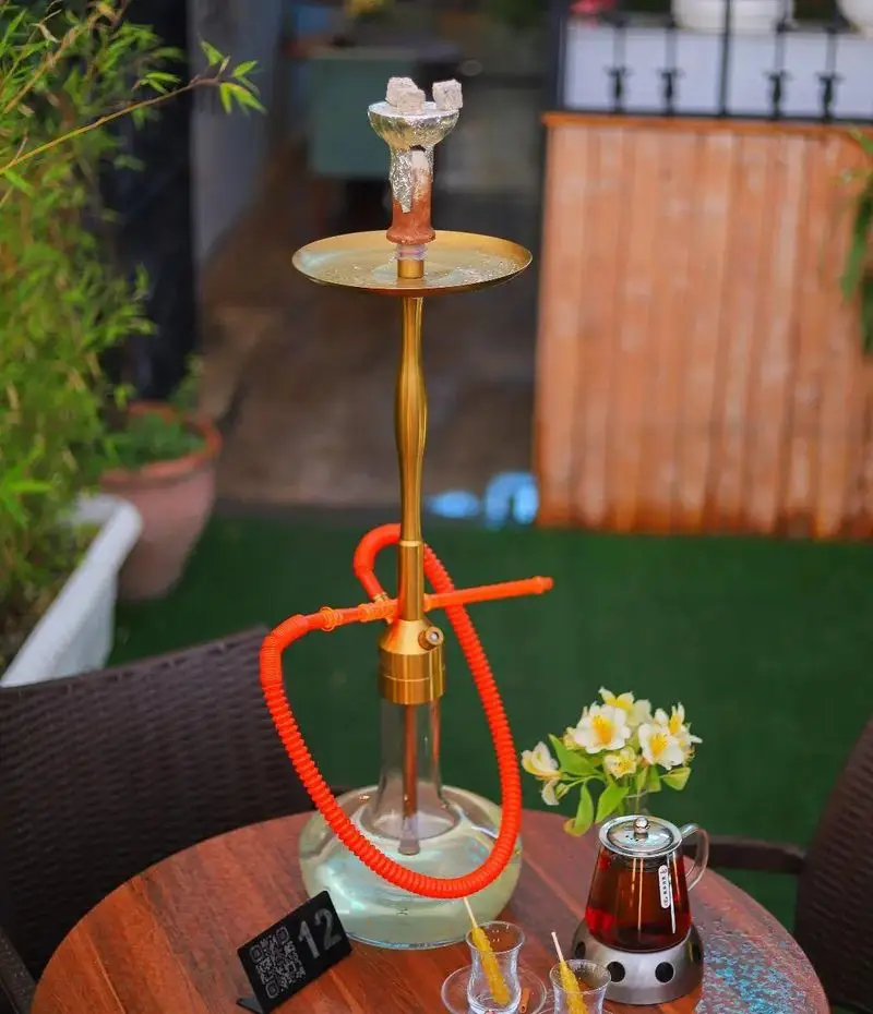 لذت قلیان لوکس طلایی، چای اصیل و نبات در فضای باز و دنج کافه بینج. انتخابی عالی برای ریلکسیشن و دورهمی دوستانه.