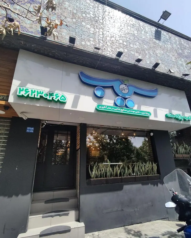 نمای بیرونی رستوران پیتزا سیب ۳۶۰، شامل لوگوی آبی‌رنگ، شماره تلفن و پنجره‌های بزرگ، نمادی از تخصص در مهندسی صنایع غذایی و هنر آشپزی.