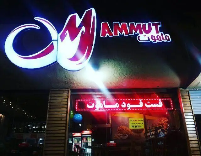 نمای بیرونی روشن و جذاب فست فود ماموت پلاس در شب با تابلوی بزرگ و نئون قرمز. لوگوی خاص و محیطی دعوت کننده برای مشتریان.