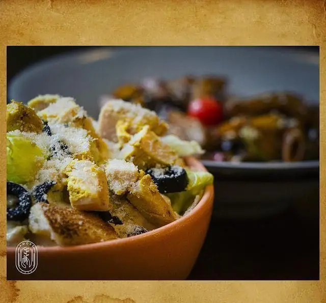 تصویری از سالاد سزار لذیذ کافه آموره: ترکیبی تازه از فیله مرغ، کروتون، پنیر پارمزان و زیتون سیاه در کاسه‌ای جذاب.