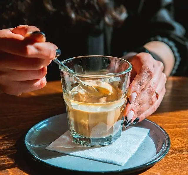 لذت نوشیدن قهوه آفوگاتو در کافه آموره. تجربه دلنشین یک دسر قهوه خوشمزه و خنک با دستانی که در حال هم زدن هستند.