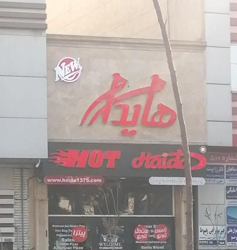 تابلوی فست فود هایدا پیروزی شامل نام "هایدا" به فارسی و انگلیسی، لوگو "New" و آدرس وب‌سایت، محلی برای سفارش ساندویچ و پیتزا با کیفیت.