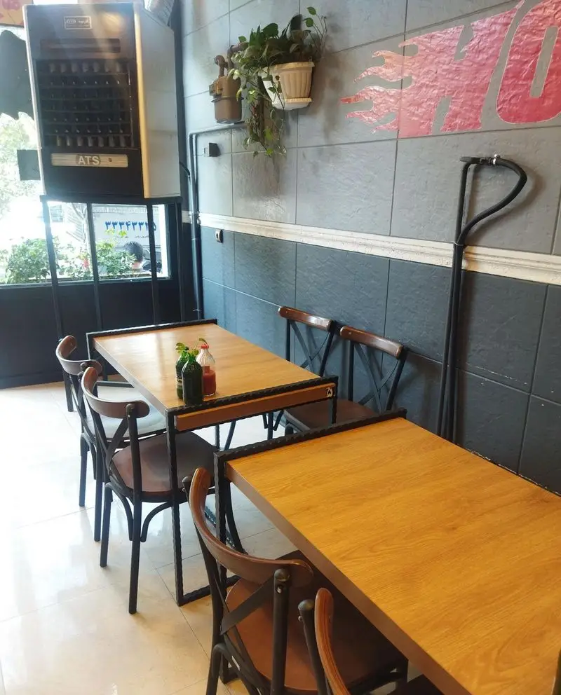 فضای داخلی و دکوراسیون مدرن فست فود هایدا پیروزی با میز و صندلی‌های چوبی، مناسب برای لذت بردن از غذا در محیطی دلنشین.