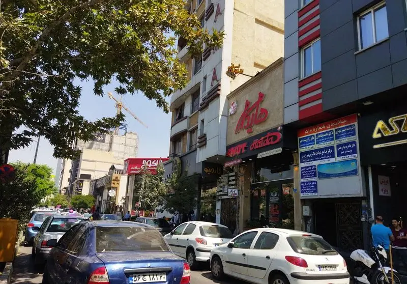 عکسی از نمای بیرونی فست فود هایدا در خیابان پیروزی تهران، با ساختمان‌ها، خودروها و فضای شهری پر جنب و جوش.