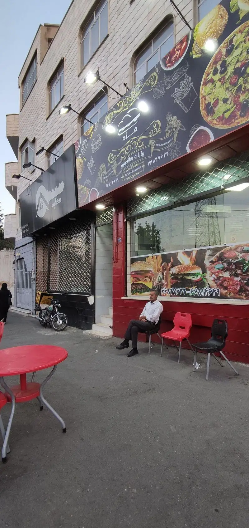 فست فود مزه: نمای بیرونی رستوران پیتزا، ساندویچ و برگر با شماره تماس ۹۹۸۲۷۲۳۲ - ۹۹۸۱۴۶۴۹ و فضای نشیمن بیرونی.