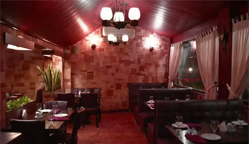 نمایی از فضای داخلی رستوران ایتالیایی ترامونتو با دکوراسیون آجری قرمز و سقف چوبی، میزهای غذاخوری آماده پذیرایی از مهمانان.