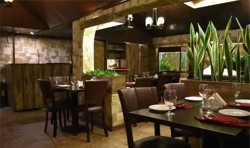 تصویری از فضای داخلی دلنشین رستوران ایتالیایی ترامونتو با میزهای آماده، آکواریوم زیبا و گیاهان دکوری که محیطی شیک ساخته.