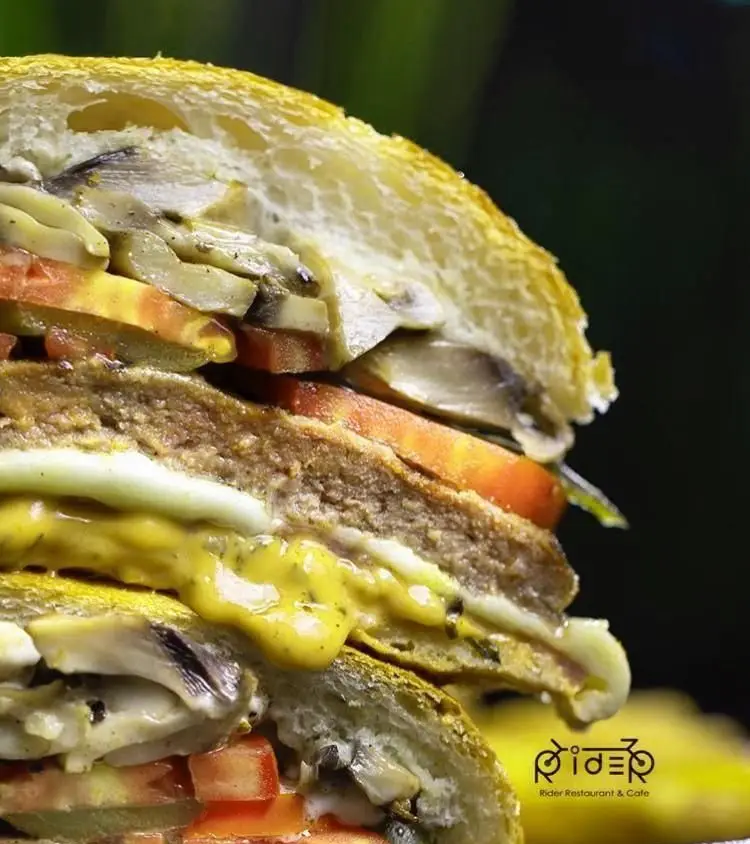 نمایی نزدیک از ساندویچ ویژه کافه رایدر با نان تازه، قارچ، گوجه، پتی گوشت و سس مخصوص. بهترین ساندویچ در رستوران و کافه Rider.
