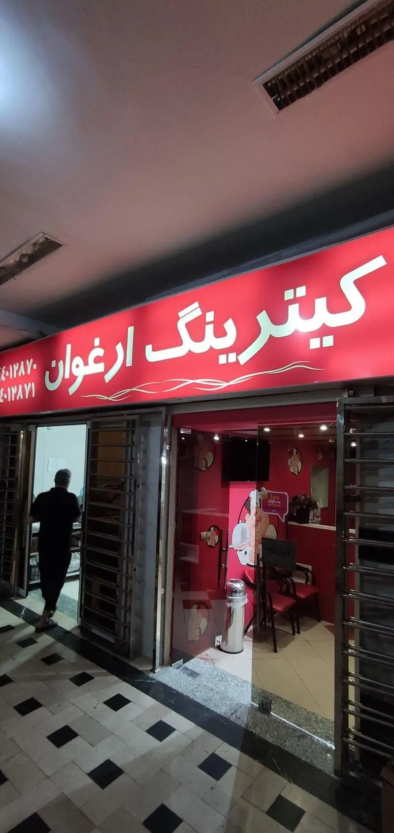 فروشگاه کترینگ ارغوان با دکوراسیون داخلی صورتی و تابلوی قرمز برجسته، ارائه دهنده بهترین خدمات غذایی و پذیرایی در منطقه.