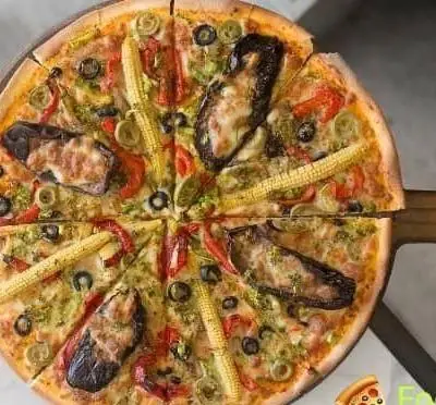 پیتزای ویژه فست فود فودینو با بادمجان کبابی، ذرت مینیاتوری، زیتون، فلفل دلمه و سس سبز، برش خورده و آماده سرو.