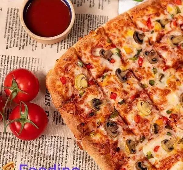 پیتزا قارچ و سبزیجات تازه و خوشمزه فست فود فودینو با سس گوجه‌فرنگی و گوجه‌های قرمز روی زمینه روزنامه، آماده سرو.