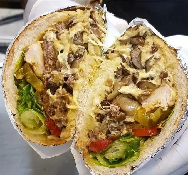 ساندویچ مرغ و قارچ پرملات فودینو با پنیر ذوب شده، کاهو و خیارشور، یک فست فود لذیذ و وسوسه‌انگیز برای علاقه‌مندان به غذاهای خوشمزه.