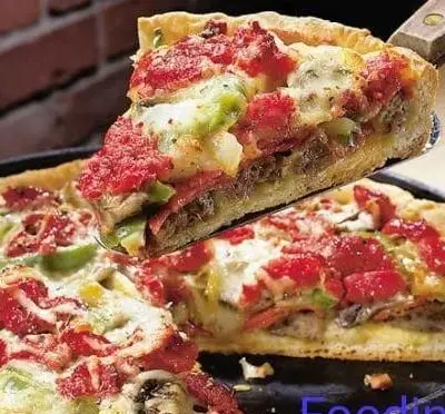 برش پیتزا دیپ دیش لذیذ فودینو با لایه‌های پنیر آب شده، سس گوجه، تکه‌های گوشت و فلفل سبز تازه. فست فود فودینو.