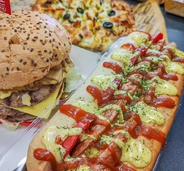 منوی کامل فست فود فودینو: همبرگر دوبل خوشمزه با پنیر، ساندویچ ویژه با سس و سبزیجات، و پیتزای ذرت و زیتون.