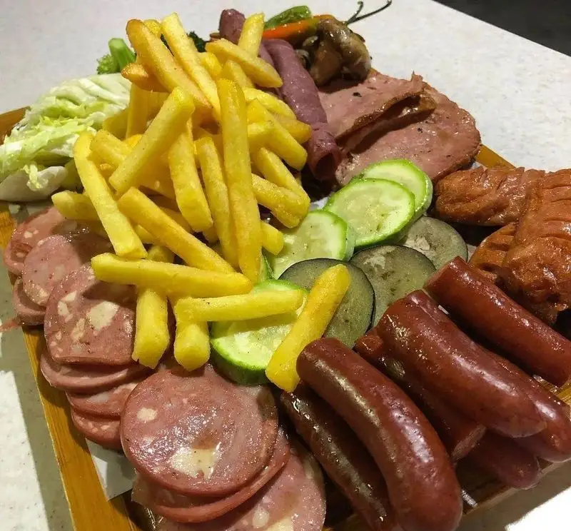 بشقاب کامل و خوشمزه سینی مزه از فست فود فودینو شامل سیب زمینی سرخ کرده، سوسیس، کالباس و مخلفات متنوع و لذیذ.