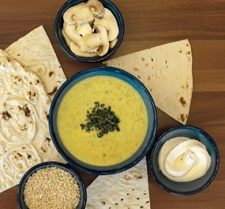 سوپ گرم و مقوی سوپ چی با قارچ و جو، سرو شده با نان تازه و خامه. یک غذای سالم و خوشمزه از مواد اولیه با کیفیت.