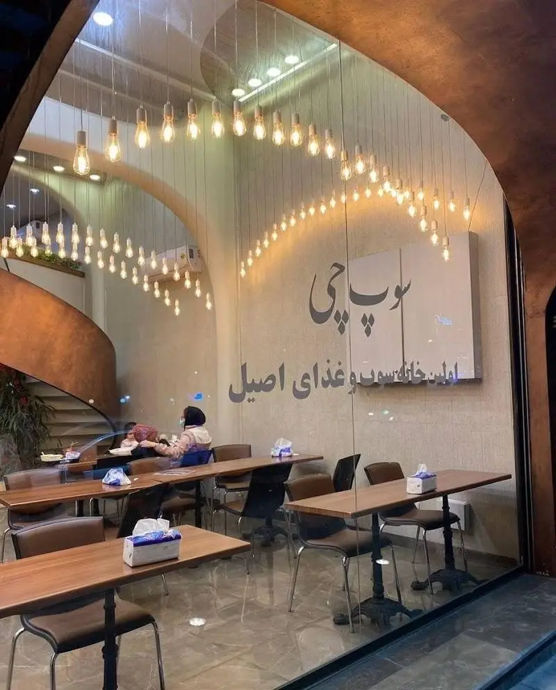 نمای داخلی شیک و مدرن رستوران سوپ چی، اولین خانه سوپ و غذای اصیل با دکوراسیون خاص، میز و صندلی چوبی و نورپردازی گرم و دلنشین.