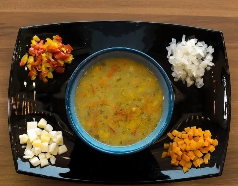 سوپ چی: یک کاسه سوپ سبزیجات خانگی با فلفل دلمه، پیاز، هویج و سیب زمینی خرد شده، آماده طبخ سوپ تازه و سالم.