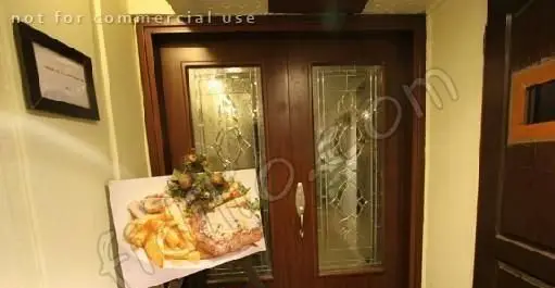 نمایی از ورودی رستوران گریل ۴۵۸ با درب‌های دوتایی قهوه‌ای شیک و شیشه‌های طرح‌دار. تابلوی عکس یک پرس غذای استیک، سیب‌زمینی و سالاد.