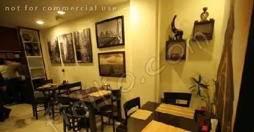 فضای داخلی دنج و شیک رستوران گریل ۴۵۸ با میز و صندلی‌های چوبی و دکوراسیون مدرن شامل تابلوهای شهری و قفسه‌های دیواری.