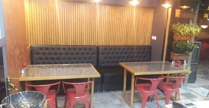 فضای داخلی مدرن و دنج کبابچی اکسپرس اکباتان با میز و صندلی‌های شیک قرمز و مبلمان چرمی مشکی، مناسب برای صرف غذا.