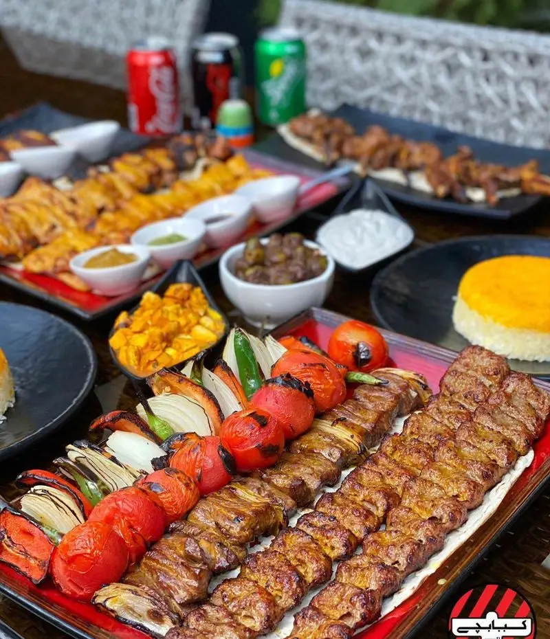 سفره ای لذیذ از انواع کباب ایرانی شامل جوجه، کوبیده و برگ در کبابچی اکسپرس اکباتان به همراه گوجه کبابی، زیتون و برنج زعفرانی.