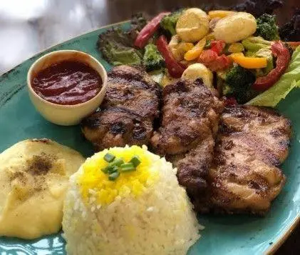 بشقاب غذای سنتی سفره خانه نارین شامل کباب لذیذ مرغ/گوشت، برنج زعفرانی، پوره سیب‌زمینی، سس و سالاد تازه رنگارنگ رستوران نارین.