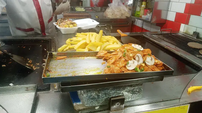 آشپزخانه شلوغ فست فود برگر تهران تک با پخت سیب زمینی سرخ کرده و برگرهای تازه روی گریل، آماده سرو غذاهای خوشمزه.