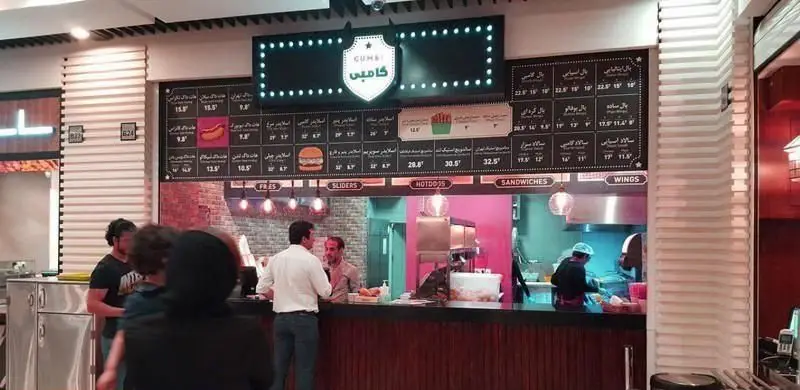 کانتر سفارشات در رستوران گامبی با منوی کامل فست فود شامل هات داگ، ساندویچ، اسلایدر، سیب زمینی و بال. تجربه غذایی عالی در محیطی مدرن.