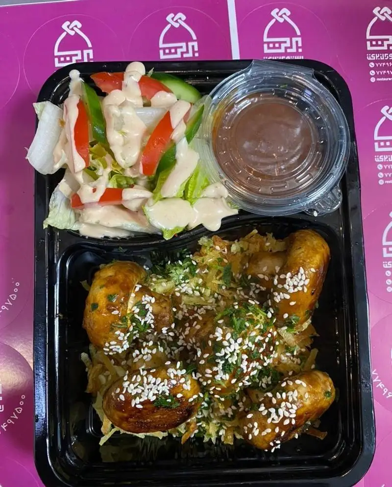 تصویری از یک پک غذایی کامل و باکیفیت از رستوران برکت، شامل مرغ کنجدی، سیب‌زمینی چیپسی، سالاد تازه و سس مخصوص. غذای ایرانی فرنگی بیرون‌بر.