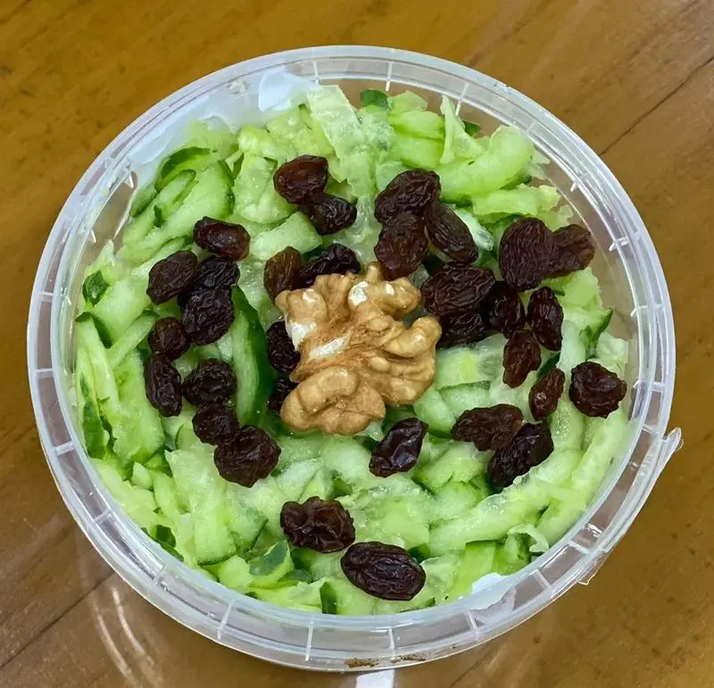 سالاد رژیمی خیار با کشمش و گردو در ظرف شفاف، انتخابی سالم و مقوی از منوی رستوران برکت (ایرانی فرنگی رژیمی صبحانه).