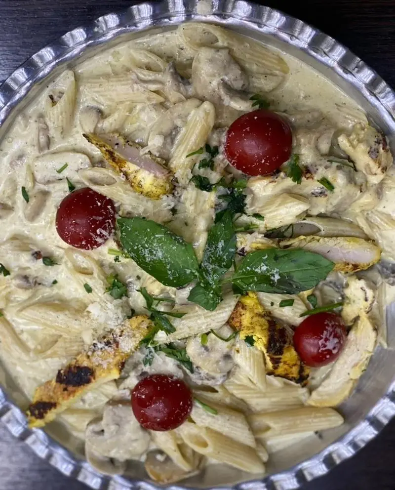 پاستا پنه خامه‌ای و خوشمزه با تکه‌های مرغ گریل شده، قارچ و گوجه گیلاسی، یک غذای فرنگی پرطرفدار از رستوران برکت.