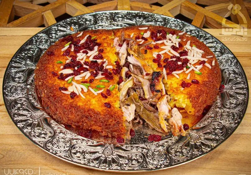 ته چین مرغ زعفرانی مجلسی با ته دیگ طلایی، زرشک و خلال بادام. غذای سنتی ایرانی خوش طعم از رستوران برکت.