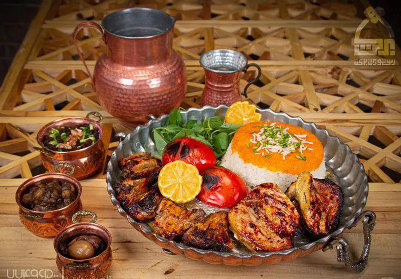 تصویری از میز غذا در رستوران برکت: کباب ایرانی، چلو زعفرانی، گوجه کبابی و خورش‌های سنتی در کنار پارچ آب مسی و دکور چوبی.